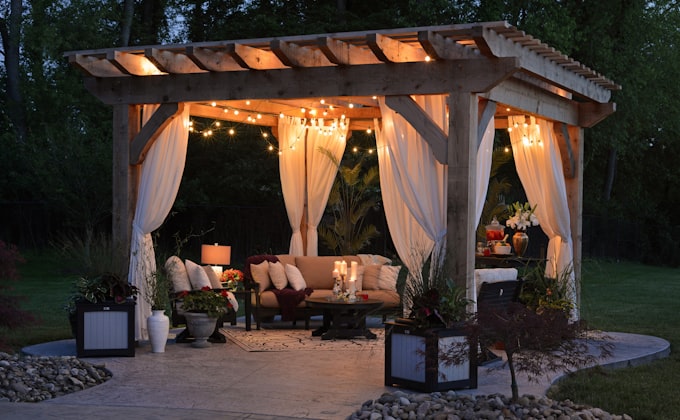 A beautifully defined outdoor living space with pergola, curtains and string lights
