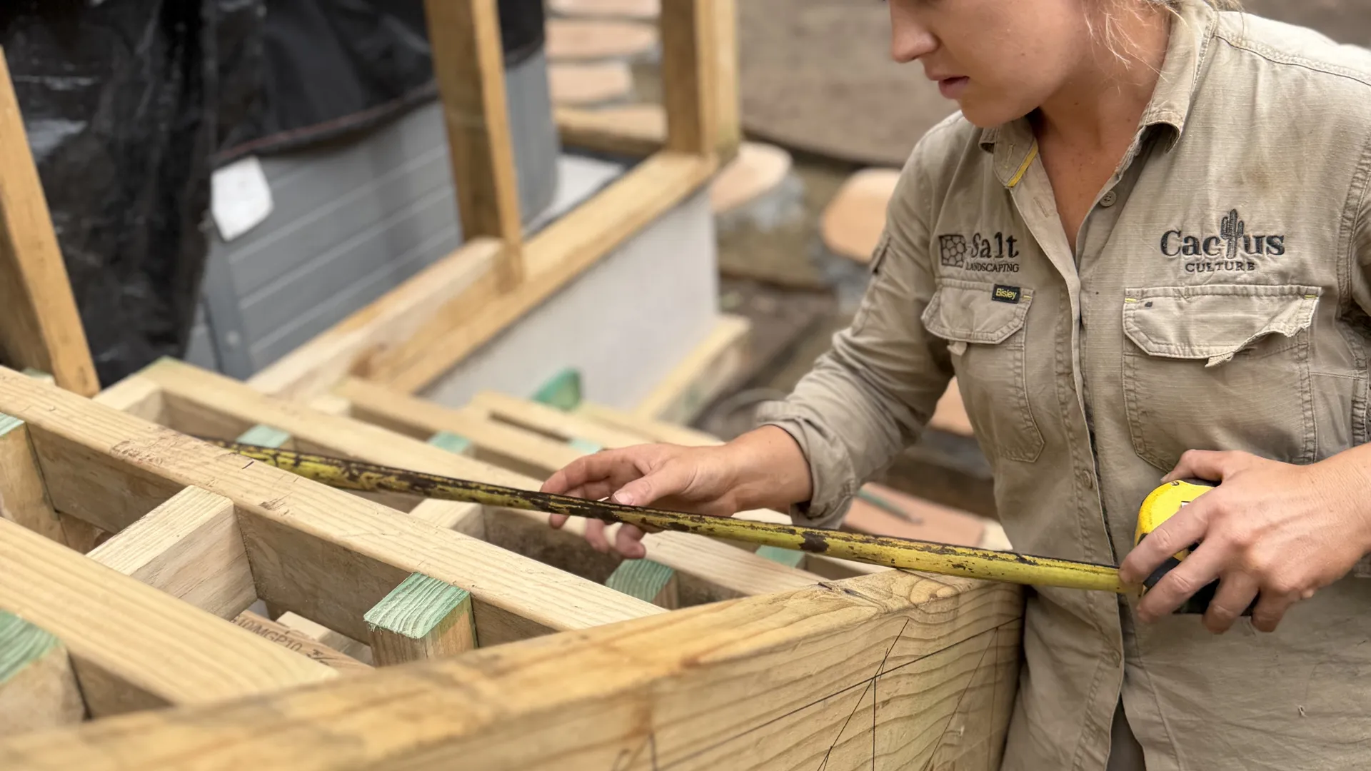 A Salt Landscaping team member measuring timber framing on a structural landscape build